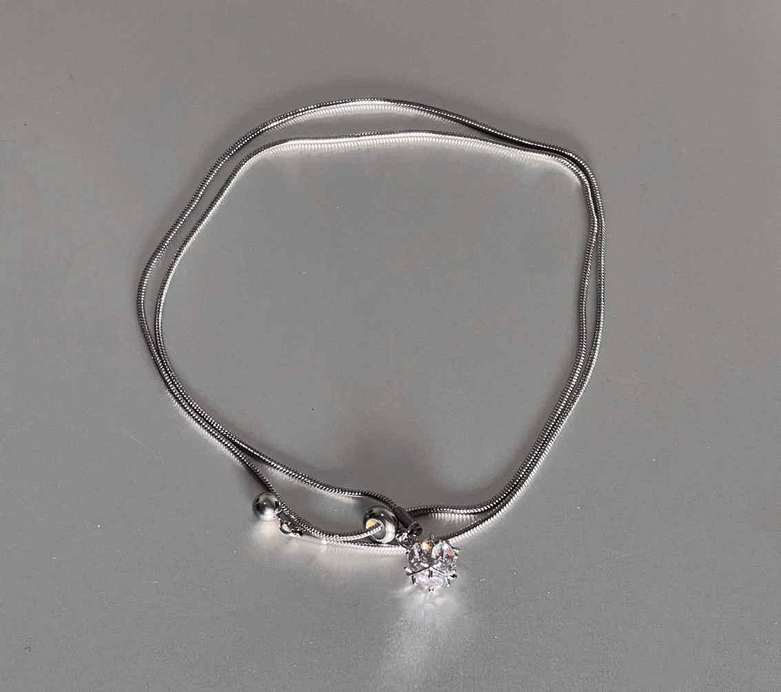 Silver necklace with a small pendant on a gray background
