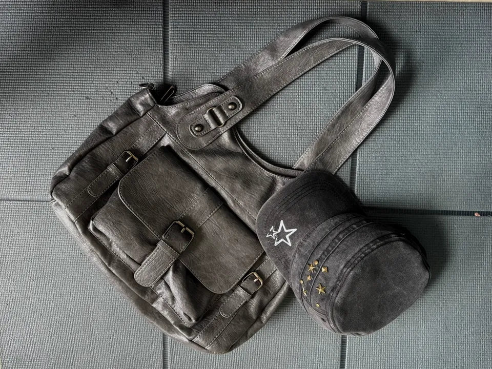 Dark leather bag and cap on a textured surface