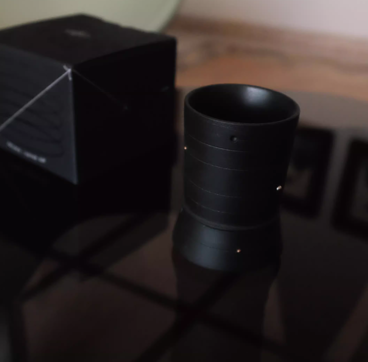 Black mug on a reflective surface with a blurred background