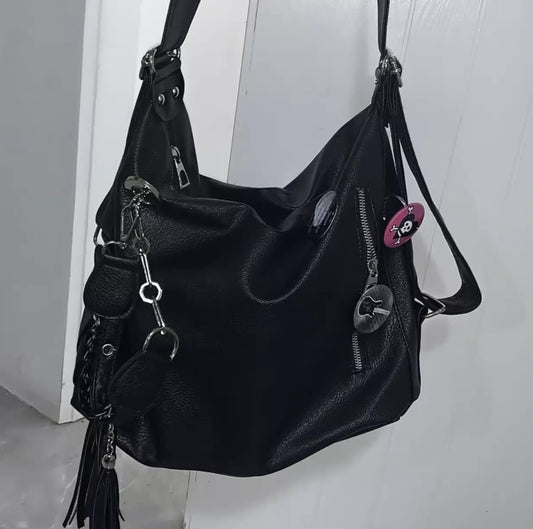 Black leather handbag with keychain on a light gray background