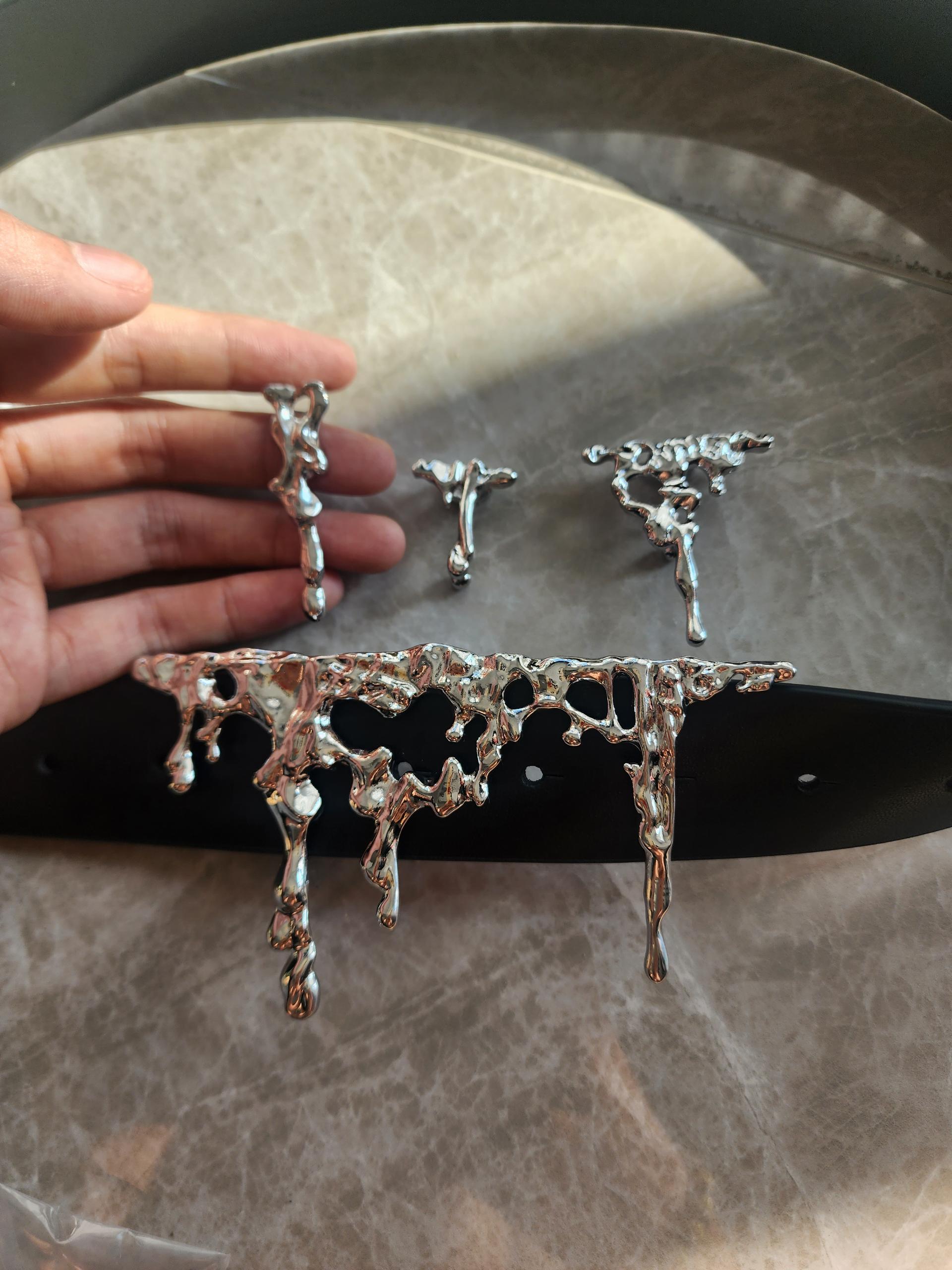 Metallic decorative items on a marble surface with a hand for scale.