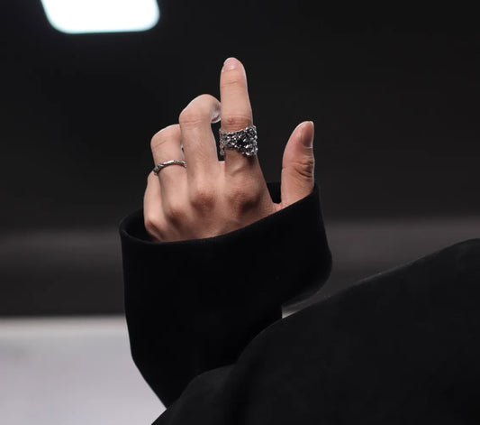 Hand wearing multiple rings with a blurred background