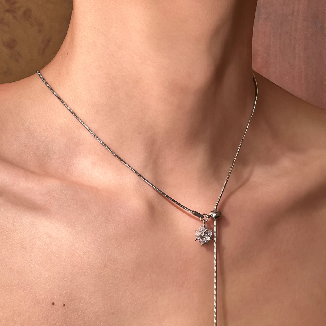 Necklace with a pendant on a person's neck against a neutral background