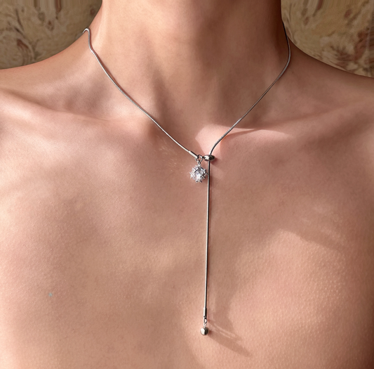 Silver necklace with a star-shaped pendant on a person's neck