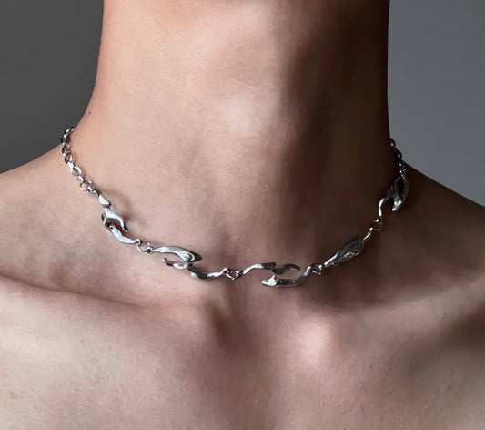 Silver chain necklace on a person's neck against a neutral background