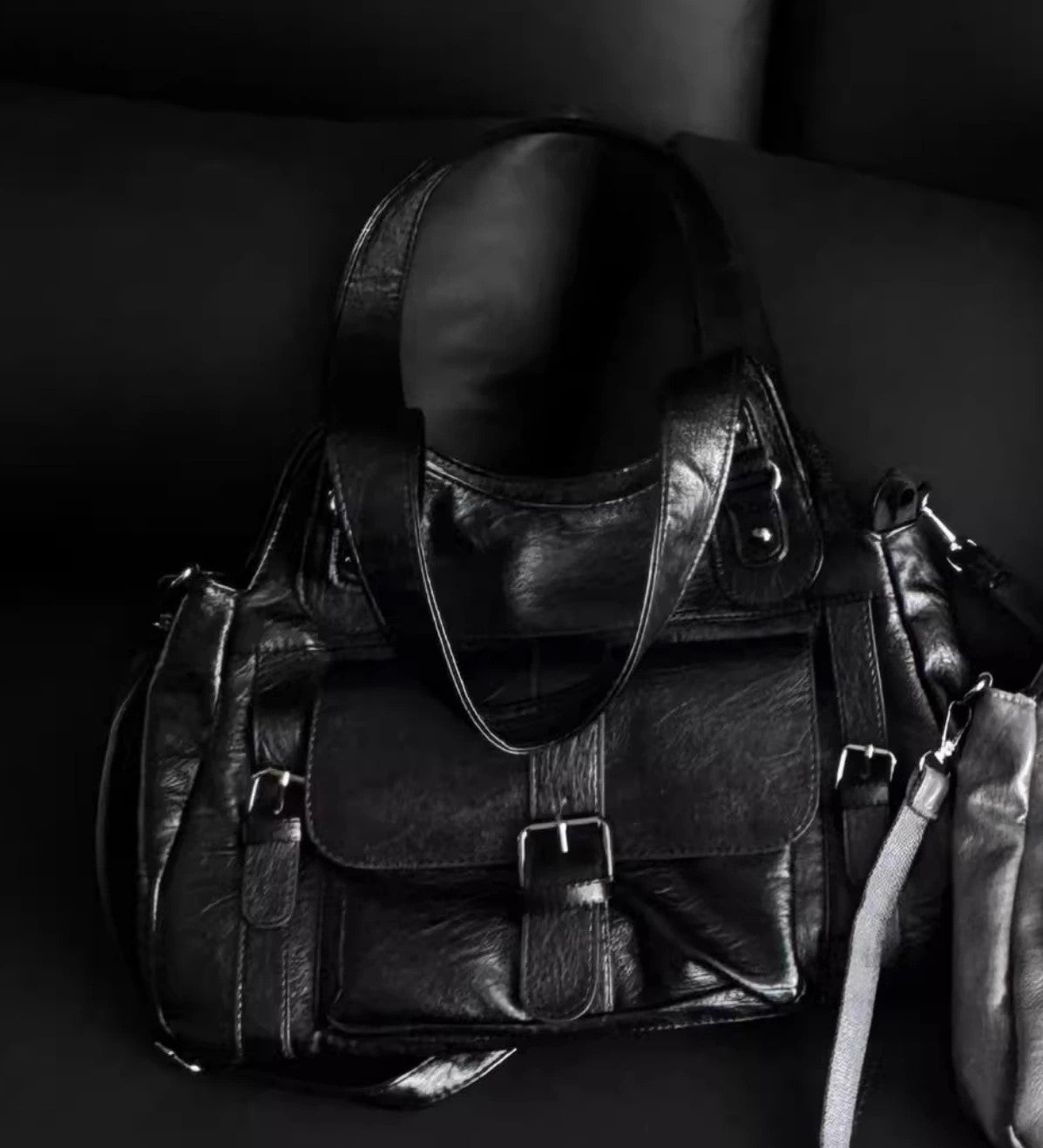 Black leather bag with a strap on a dark background