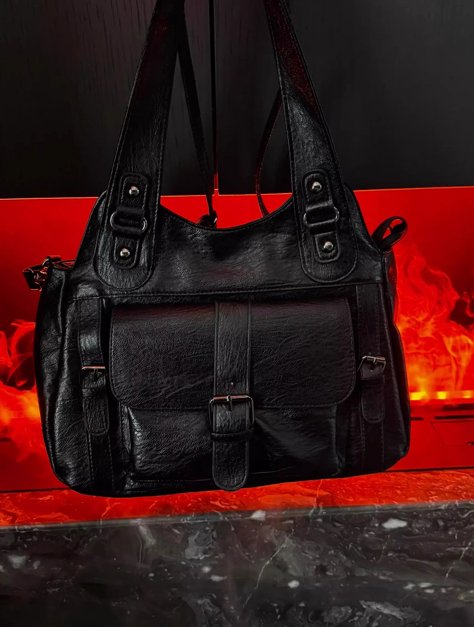 Black leather handbag on a reflective red surface with a dark background