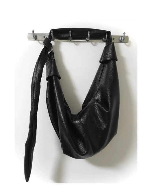 A slouched silhouette with tension and elegance. Crafted in matte black with drawstring detail, this bag carries quiet power and dark intent.