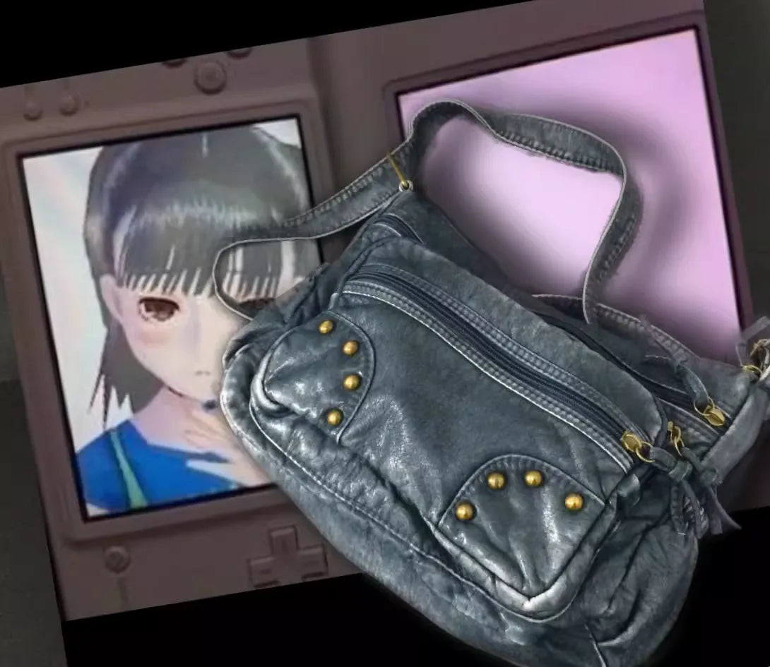 Gray handbag with gold studs in front of a computer screen displaying an anime character.