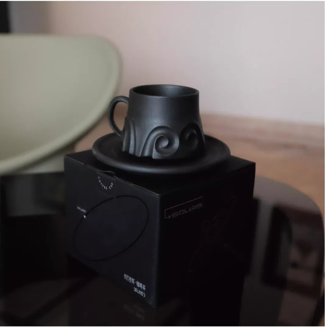 Black mug on a black electronic device with a blurred background