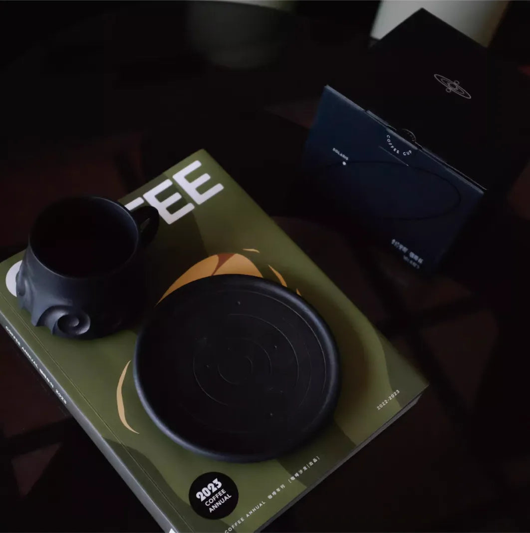Green book with a black cup and lid on top, featuring '2023' and 'FEE' text.