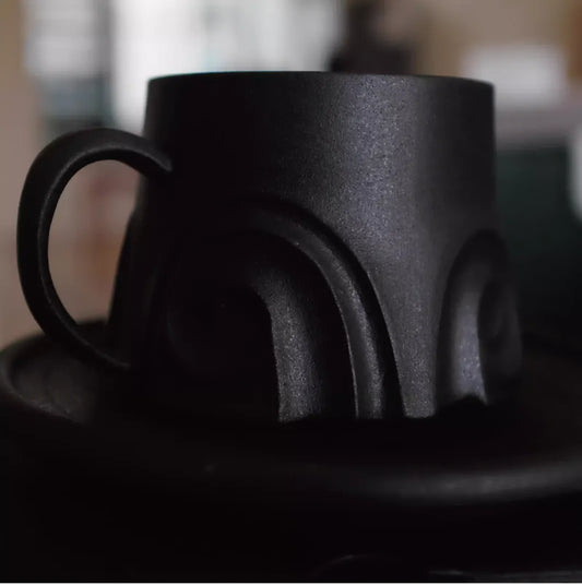 Black ceramic teapot with a textured surface on a blurred background