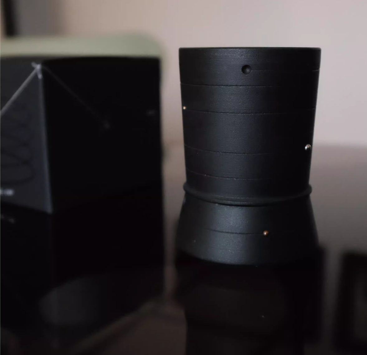 Black cylindrical object on a reflective surface with a blurred background