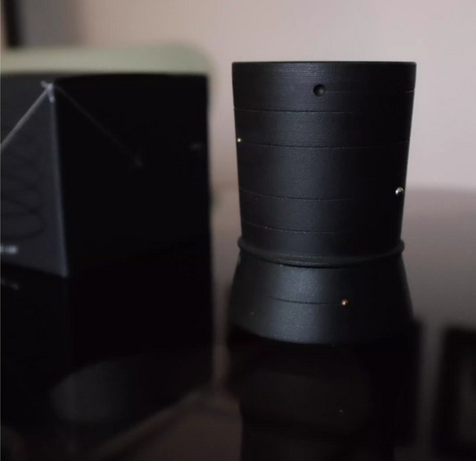 Black cylindrical object on a reflective surface with a blurred background