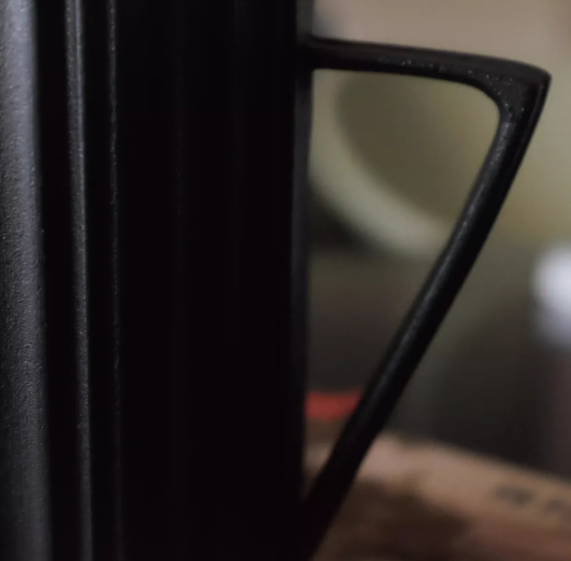 Close-up of a black mug handle with a blurred background