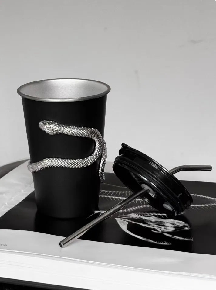 Black cup with snake design on a white surface
