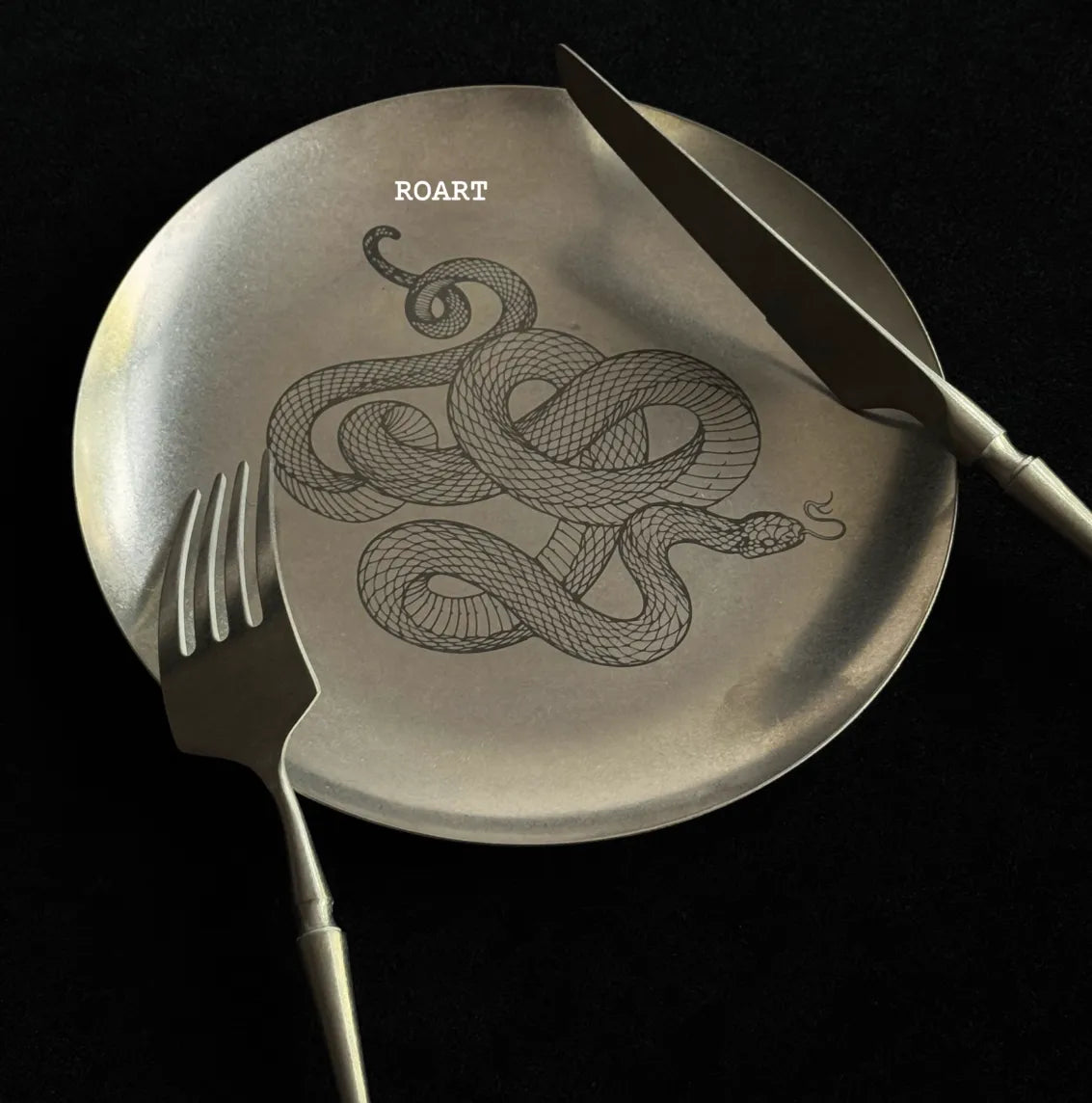 Metallic spatula with snake design and 'ROART' branding on a black background